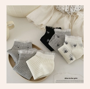 Detailed display of lace trim socks with bow embroidery on textured fabric background