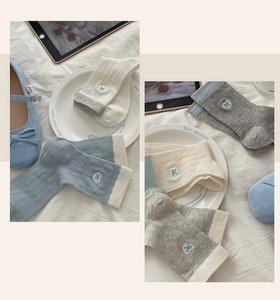 Detail of summer cotton socks with delicate bow embroidery and contrast trim in soft colors