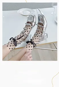 Gros plan de chaussures Mary Jane argentées avec chaussettes en tulle noir à pois