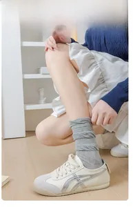 Détail de chaussettes grises en maille côtelée à haute élasticité et baskets blanches