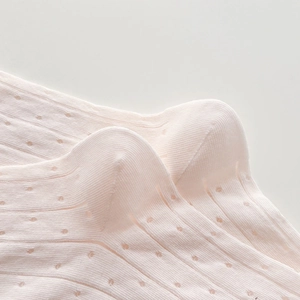 Macro detail of light pink knit socks with delicate pointelle patterns and ribbing
