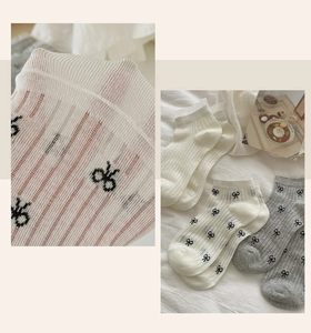 Detailed knit texture of white lace socks with black bow patterns and wavy edges
