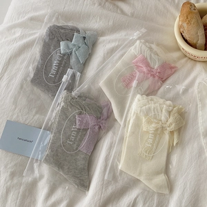 Lolita mesh crew socks with large back bows in cream colors on beige background