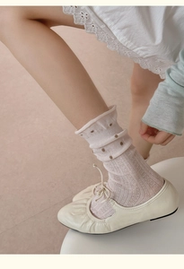 Detail von cremefarbenen Ballerinas mit Schleife und weißen Polka-Dot-Stricksocken