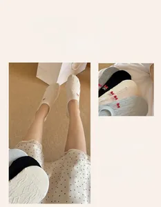 Detail of hollow-out mesh socks with red strawberry and bow embroidery patterns