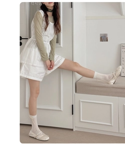 Détail de chaussettes blanches en maille avec nœuds en cuir et ballerines en soie