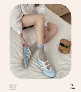 Detail of grey knitted socks with heart embroidery paired with blue Mary Jane shoes
