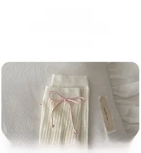 Détail de chaussettes mi-mollet en maille côtelée crème avec nœud rose et texture douce