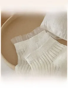 Detail of white lace socks with elastic wavy edges and delicate knit texture close-up