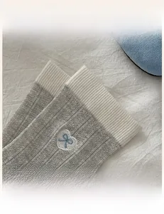 Macro detail of elastic ribbed cuff and heart bow embroidery on gray knit socks