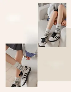 Detail of crew socks with cream base and grey geometric patterns paired with retro sneakers