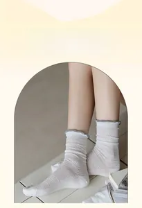 Detail of white cotton crew socks featuring grey ruffled edges and hollow herringbone knit