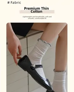 Close-up of white cotton socks with grey ruffled edges and geometric cutout texture