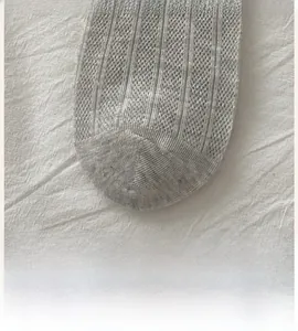 Macro detail of the smooth seamless toe construction on light gray knit cotton socks