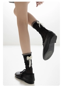 Gros plan de chaussettes noires avec nœuds en dentelle blanche et texture côtelée fine