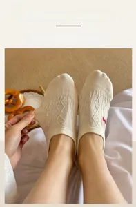 Close-up of beige cotton sock showing elastic ribbed cuff with bow strawberry embroidery