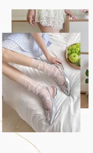 Detail of silver Mary Jane shoes with pink bows paired with white mesh socks on bed