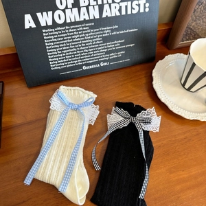Close-up of ribbed knit socks featuring delicate lace edges and plaid ribbon bows