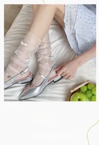 Detail of white mesh lolita socks with bow accents paired with silver pointed ballet flats