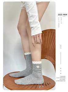 Detail showing grey knit socks with white polka dot cuffs and pink heart embroidery