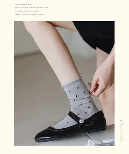 Detail of grey crew socks with black polka dots paired with pearl buckle Mary Jane shoes