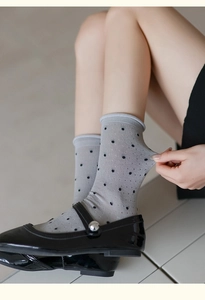 Close-up of stretchy gray polka dot crew socks styled with black Mary Jane shoes