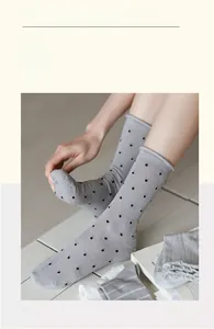 Detailed view of gray cotton crew socks with black polka dots and breathable mesh texture