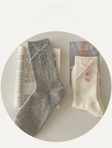 Detail of ribbed knit socks with ribbons and buttons in grey and cream white
