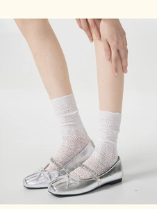 Detail of white hollow lace socks paired with silver metallic Mary Jane ballet flats