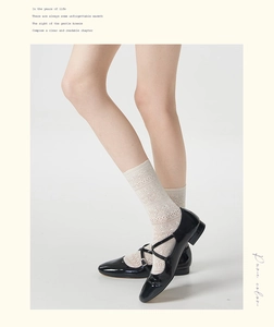 Detail of white lace hollow mesh socks paired with black patent leather Mary Jane shoes
