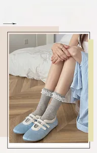 Detail of grey cotton socks with white lace trim paired with blue Mary Jane shoes