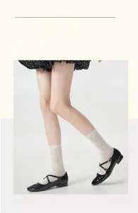 Close-up of white mesh hollow lace socks paired with black patent leather Mary Jane shoes