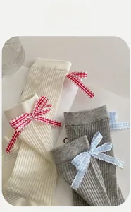 Détail de chaussettes en maille filet avec des nœuds vichy décoratifs en crème et gris