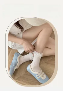 Detailed view of white cotton socks with elegant lace ruffles on model with wood floor