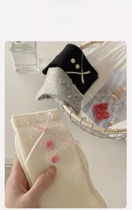Close-up of cotton socks featuring decorative buttons and silk ribbon bow accents