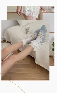 Close-up of light blue Mary Jane shoes with cream straps and white lace socks for women