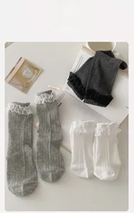 Three pairs of lace trim mid-calf socks in white and grey on a cozy desktop setting
