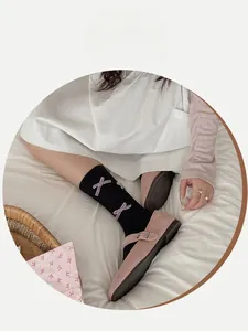 Detail of black mid-calf socks with purple velvet bow and pink Mary Jane shoes