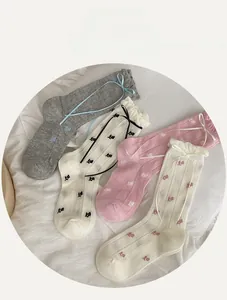 Detail of floral socks with ribbon bows and ruffled cuffs in soft pastel colors