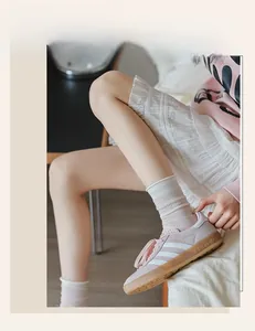 Close-up of pink suede Gazelle sneakers with white stripes and mesh socks