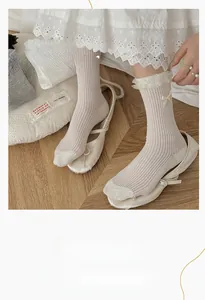 Detail of cream white lace mid-calf socks with silk bows and ribbed cotton texture