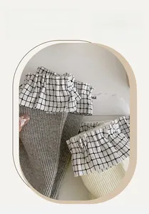 Dettaglio di calzini Lolita grigi e beige con bordo in pizzo a scacchi bianchi e neri