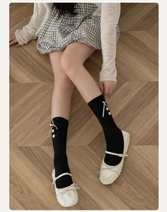 Detail of black ribbed socks with white bow and button decor paired with Mary Janes
