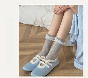 Close-up of light grey socks with white lace trim and blue Mary Jane shoes on wood floor