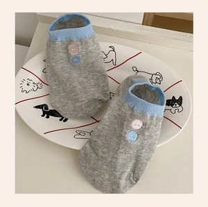 Detail of light gray low-cut socks with blue ribbed cuffs and decorative buttons