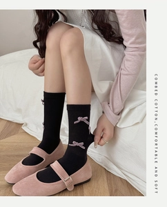 Detail of ribbed black socks with purple velvet bow and combed cotton fabric label