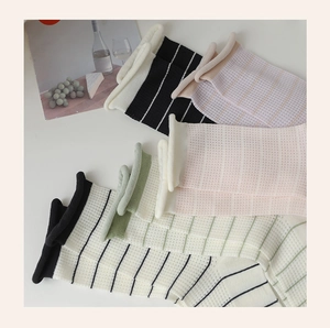 Detail of waffle knit striped mid-calf socks with rolled cuffs in various colors