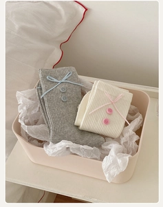 Detail of sweet Japanese style crew socks with ribbon bow and button accents in a gift box