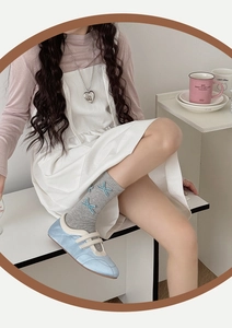 Close-up of light blue Mary Jane shoes with velvet finish and grey bow socks