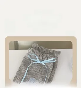 Detail of grey floral socks featuring soft elastic ruffled cuffs and light blue silk bows